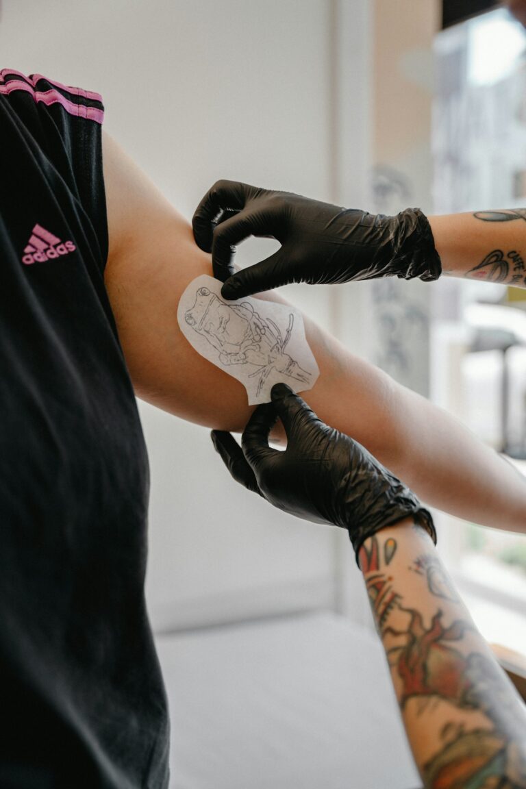 Tattoo healing process: artist applying a protective film over a fresh arm tattoo