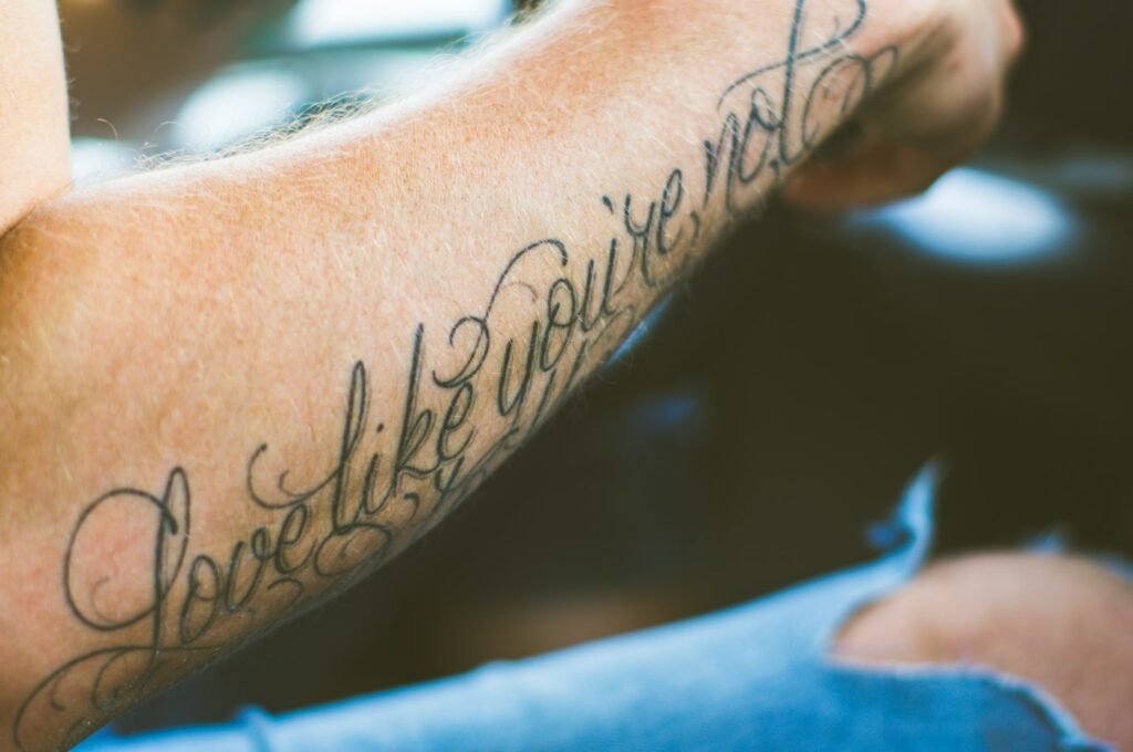 Tattoo quotes: flowing cursive quote tattoo along the forearm
