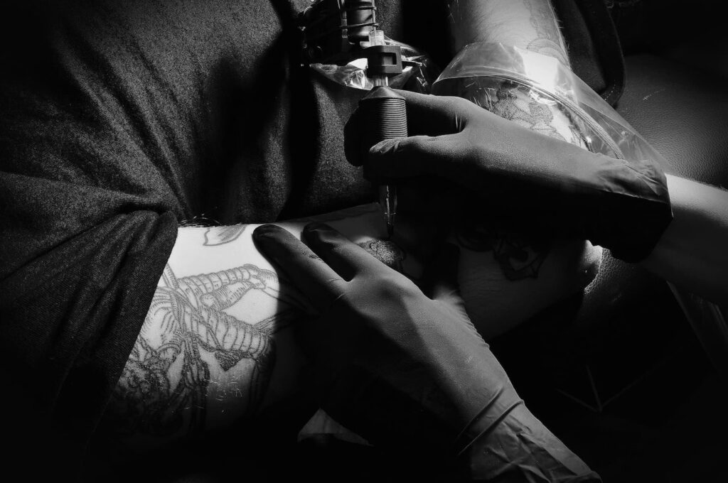 Black and white photo of a tattoo session on the arm