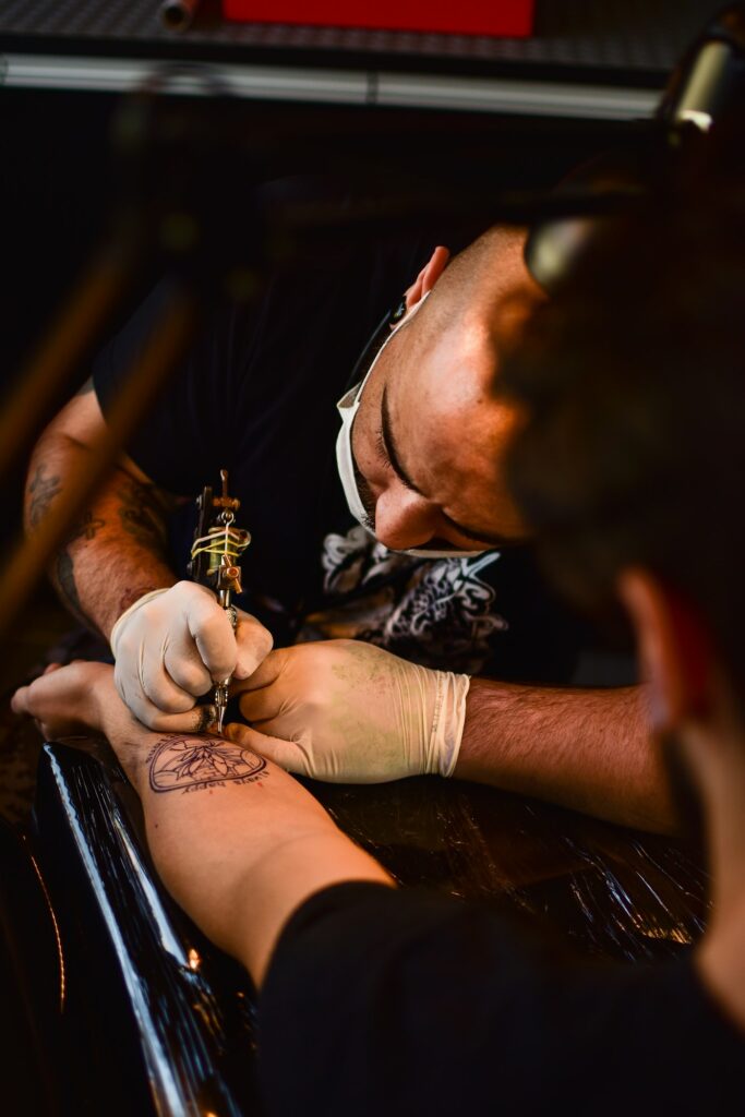 Tattoo artist working on an arm tattoo in a studio