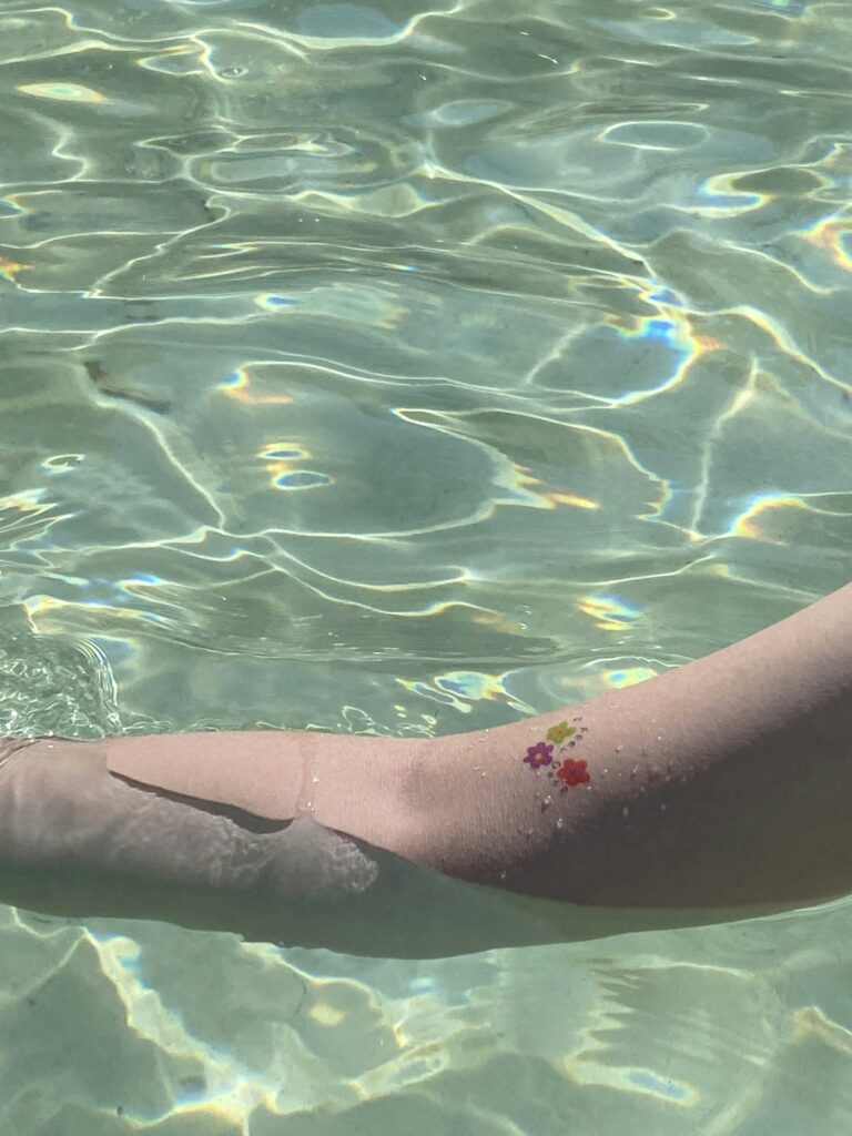 Tattooed arm resting in clear pool water