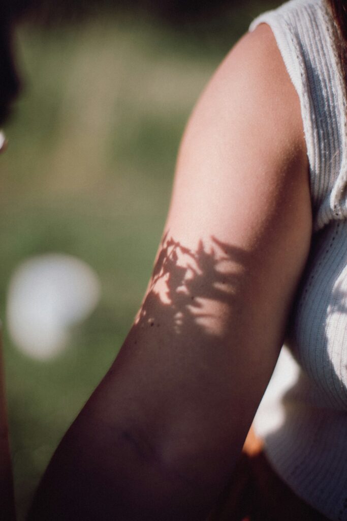 Tattooed upper arm in strong sunlight with leaf shadows