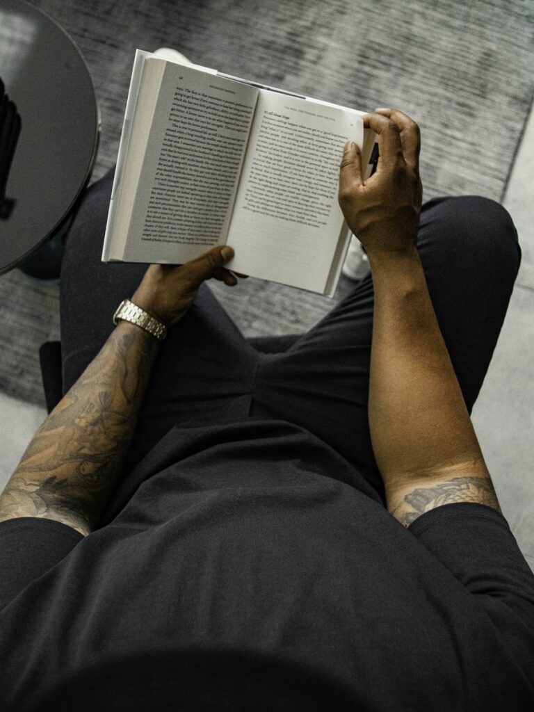 Tattooed forearms holding an open book