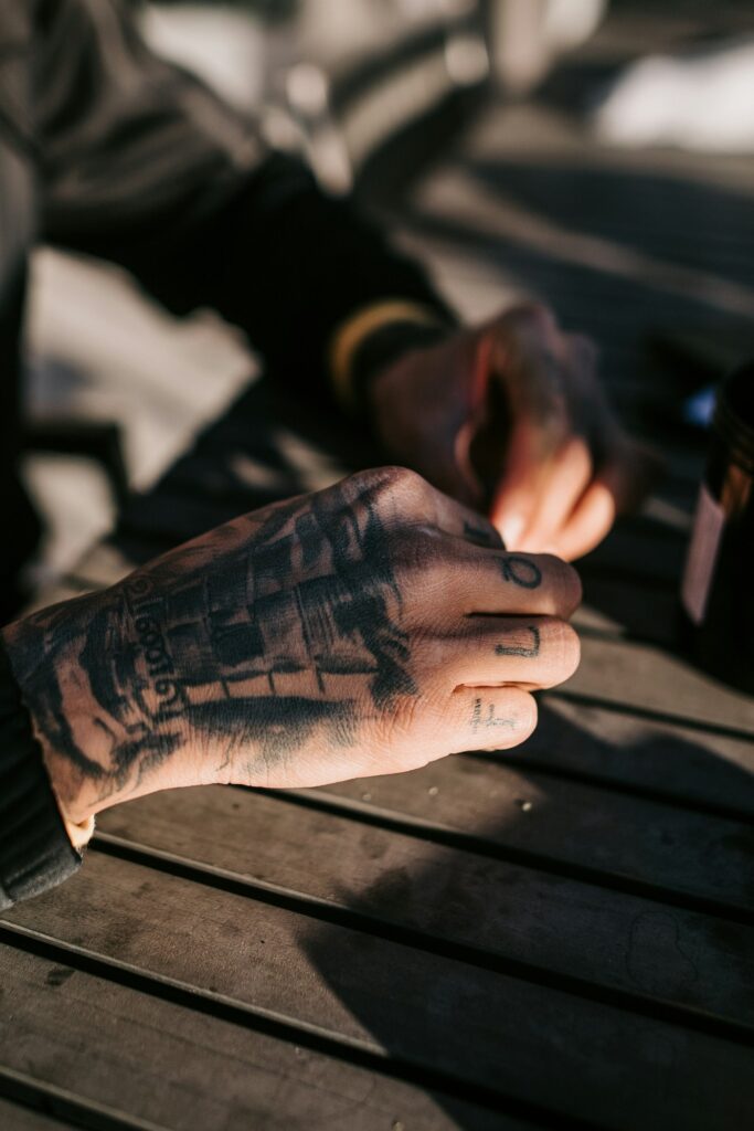 Heavily tattooed hands resting on a wooden table