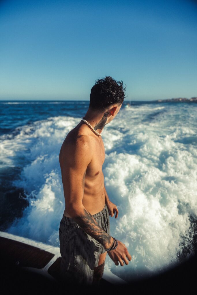 Tattooed man standing by ocean waves