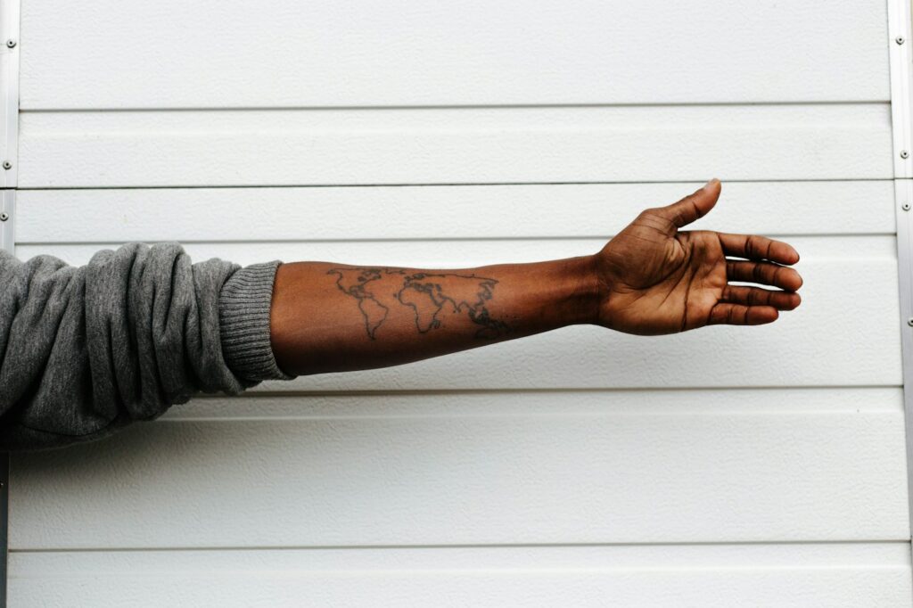 Tattoos on dark skin: black line work tattoo on an outstretched forearm