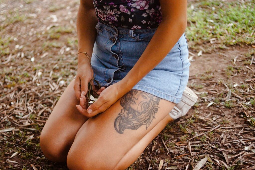 Thigh tattoos for women: woman in a denim skirt with a thigh tattoo