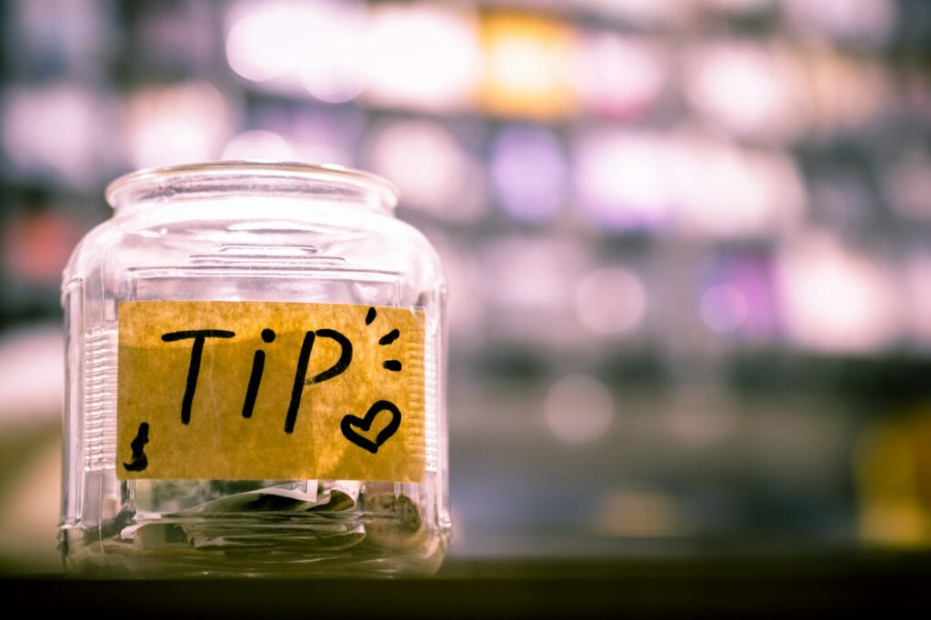 Glass tip jar with a handwritten TIP label
