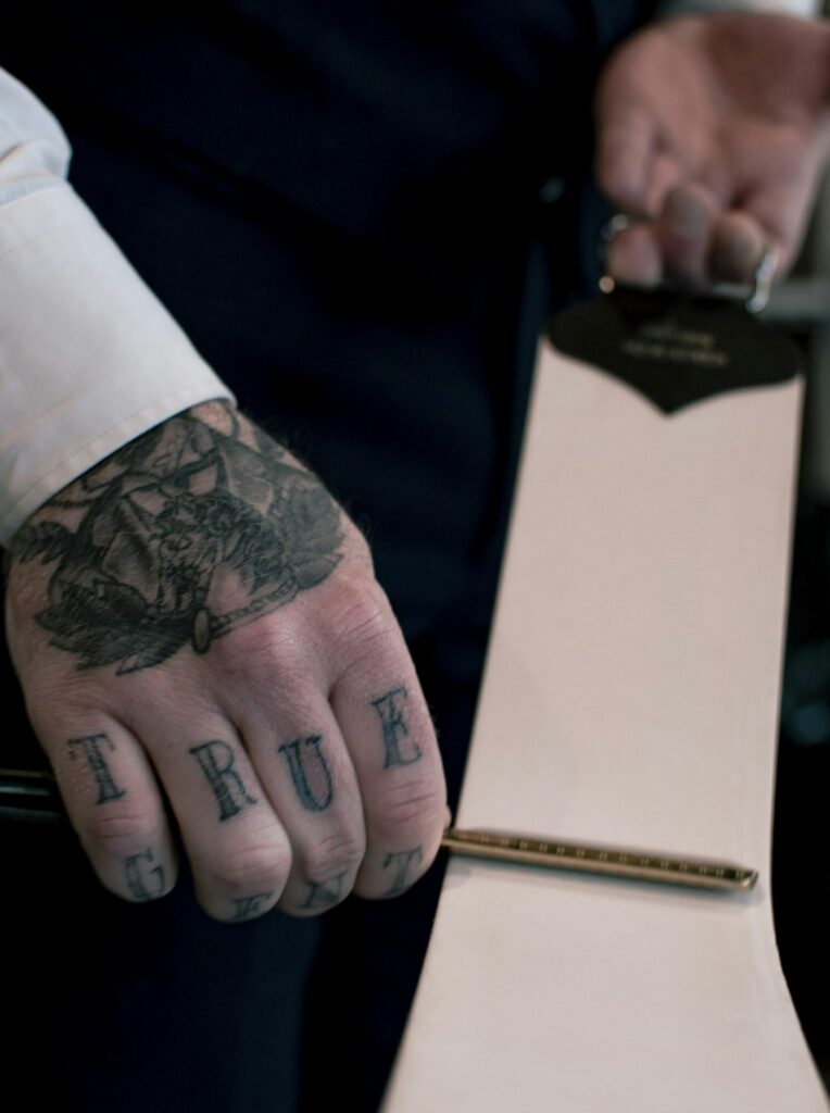 Traditional knuckle letters with a black and grey hand tattoo