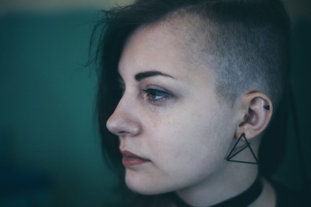 Geometric triangle tattoo behind the ear on a woman with a shaved side