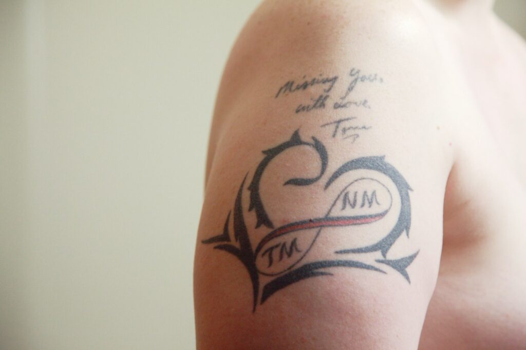 Tribal heart tattoo with initials on the upper arm
