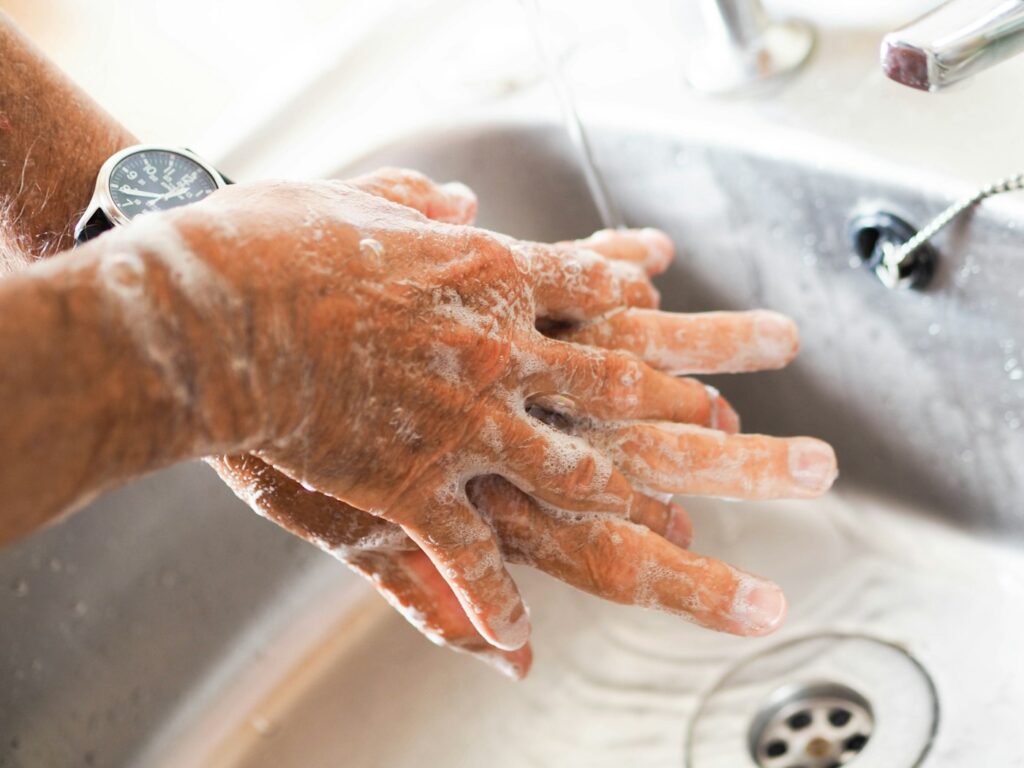 Washing hands with soap at the sink before touching a tattoo