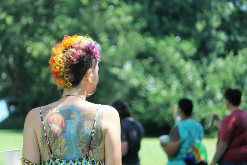 Colorful watercolor style back tattoo on a woman with rainbow hair