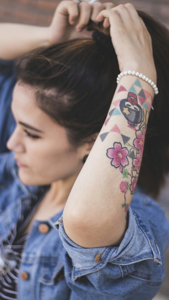 Watercolor style flowers and shapes on a woman's forearm