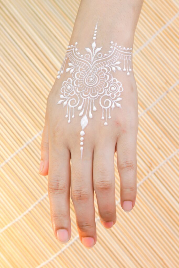 White henna lace design on the back of the hand