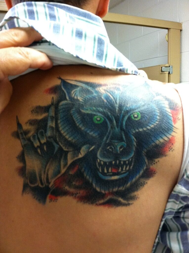 Dark wolf head cover up tattoo on the shoulder blade