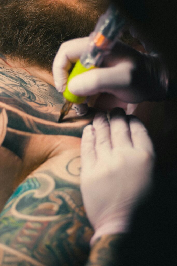 Artist packing yellow ink into a large color tattoo