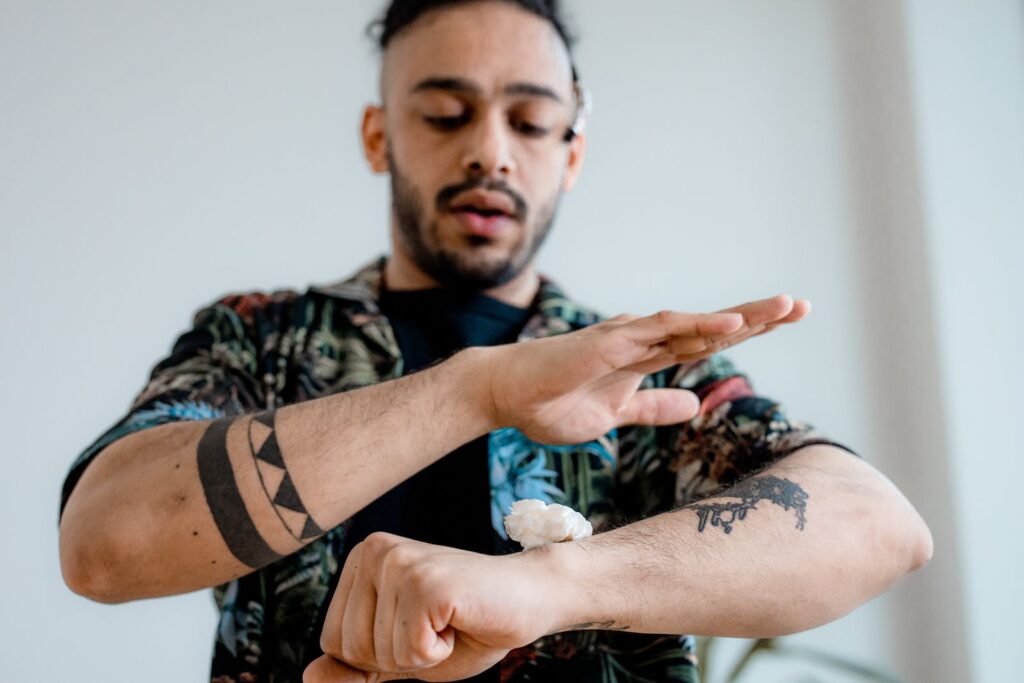 Man applying lotion to his forearm tattoo