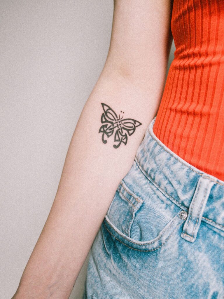 Black butterfly tattoo on a woman's inner forearm