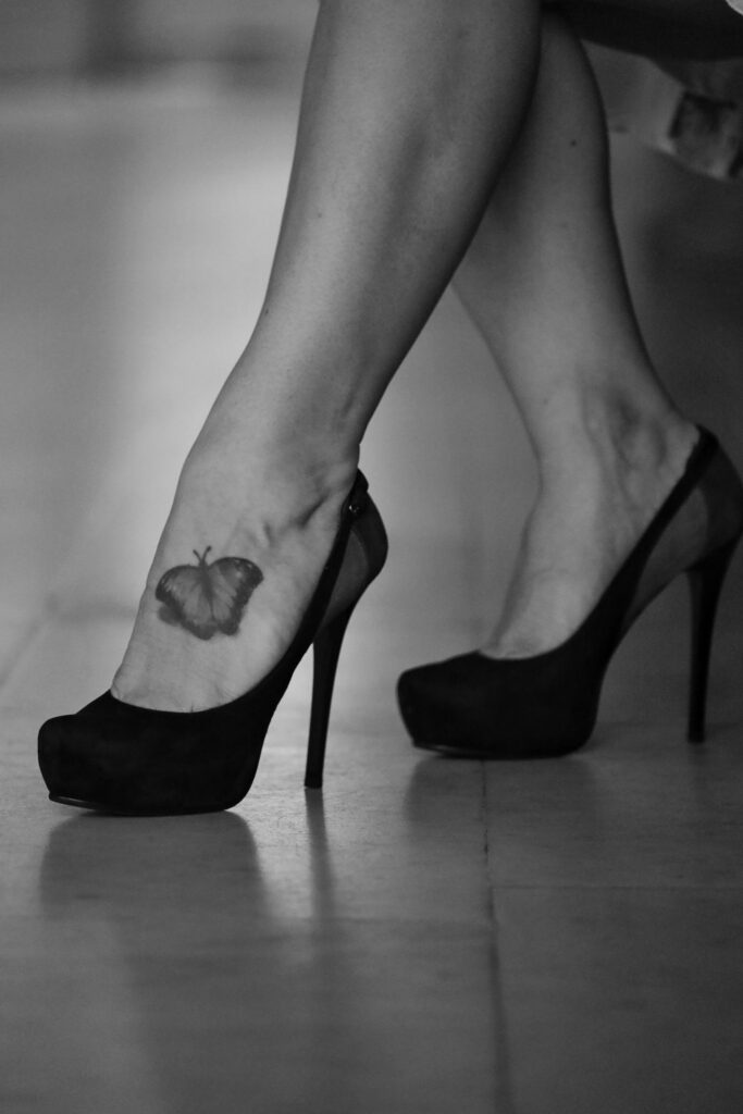 Butterfly tattoo on the ankle above black high heels