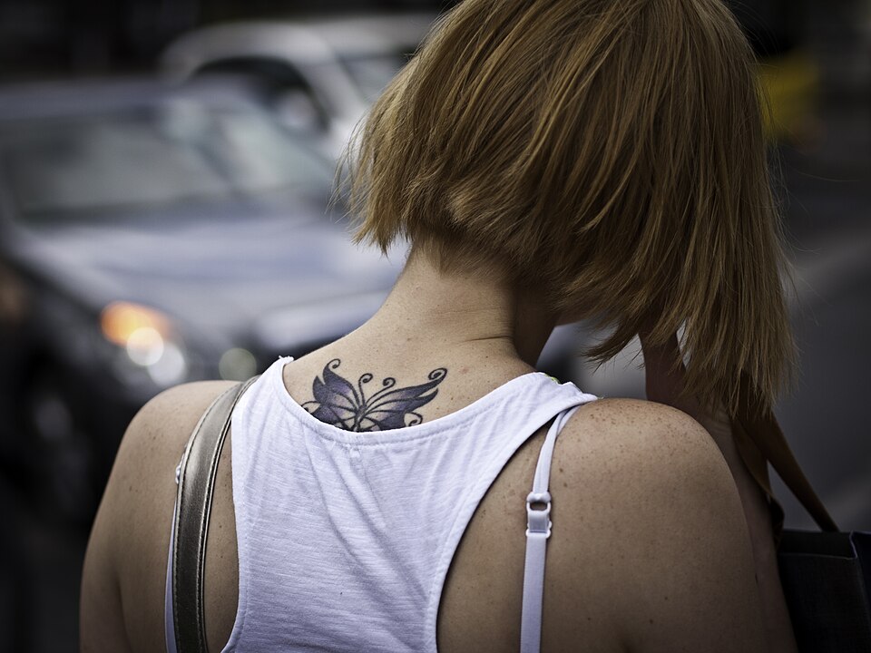 Small butterfly tattoo on the back of the neck