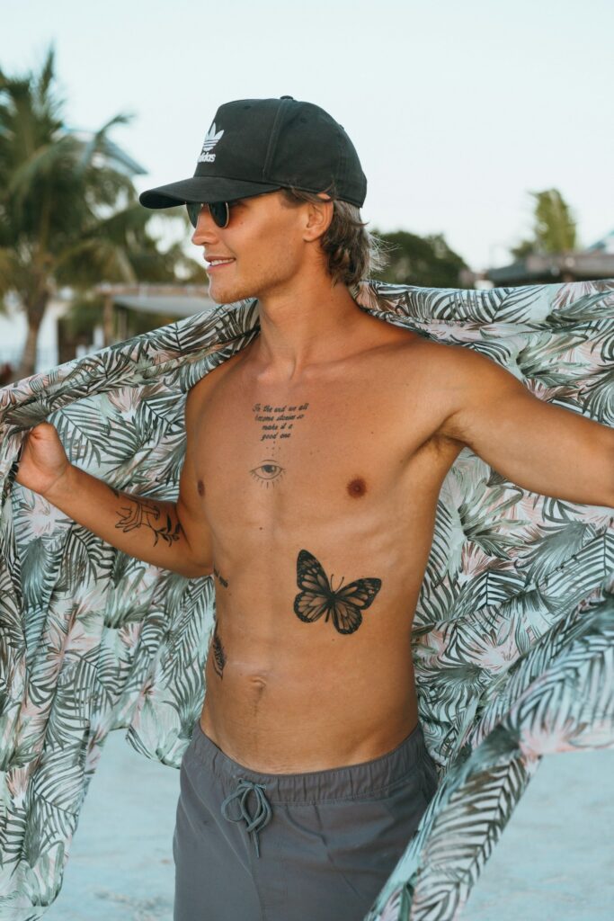 Man with a butterfly tattoo on his stomach at the beach