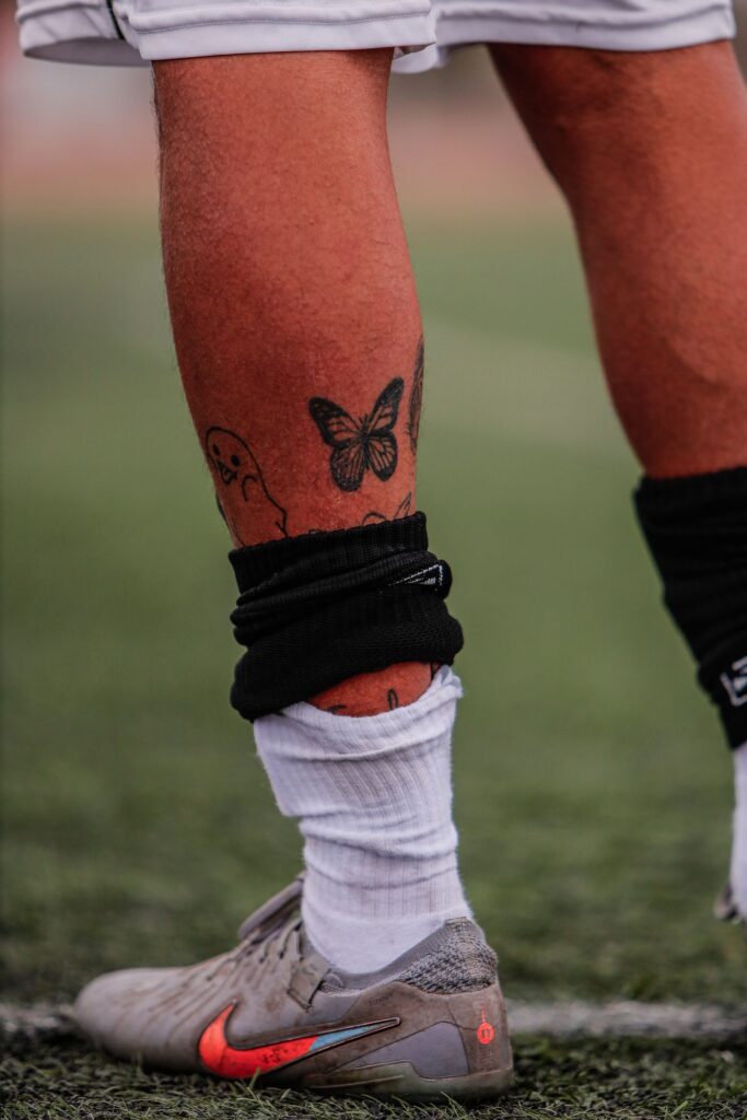 Footballer with a butterfly tattoo below the knee