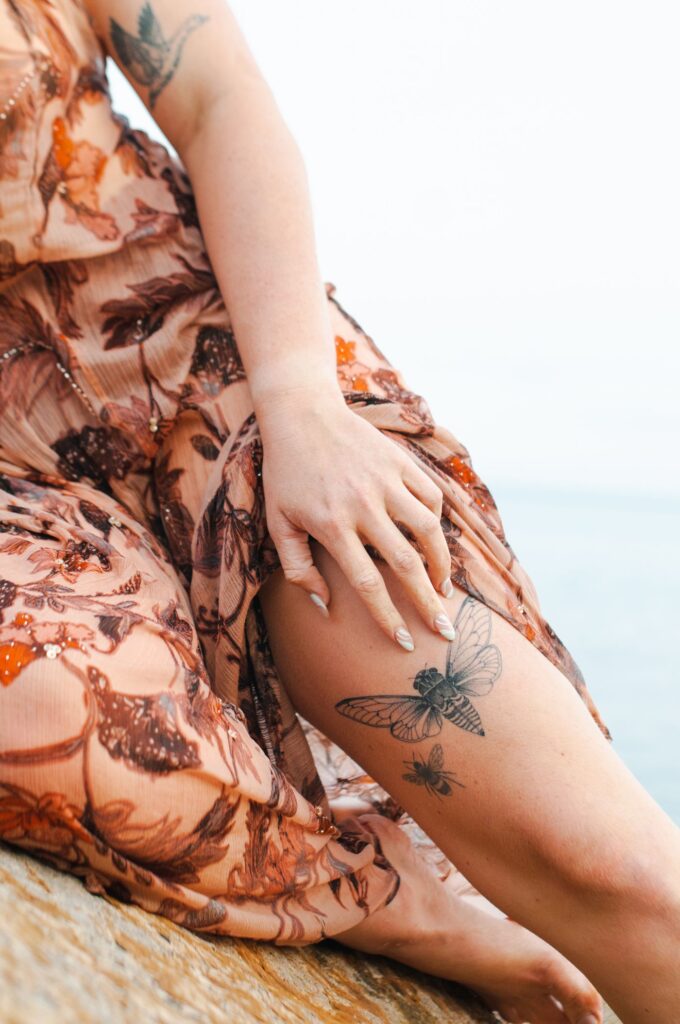 Butterfly tattoo on the thigh peeking from a floral dress