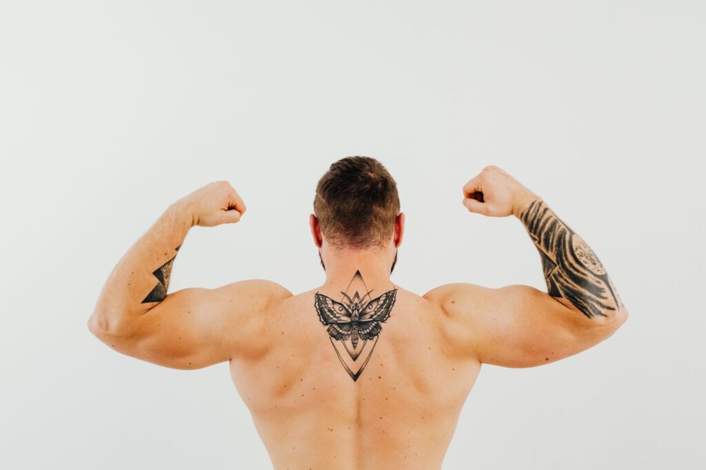 Man flexing with a butterfly tattoo between the shoulder blades