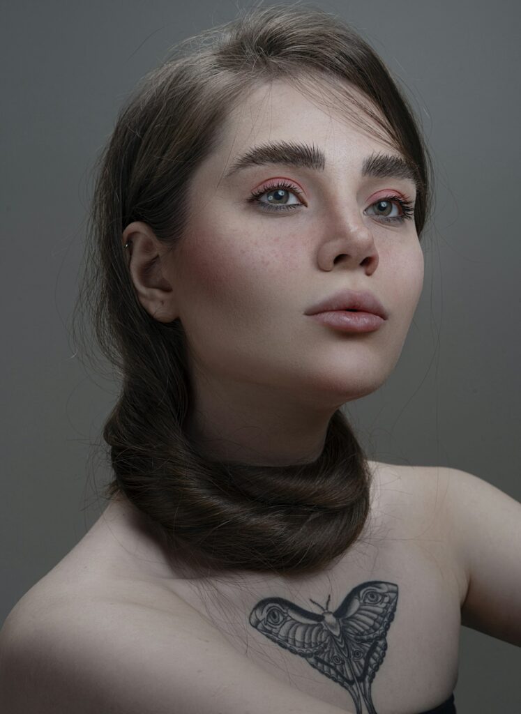 Woman with a delicate butterfly tattoo below the collarbone