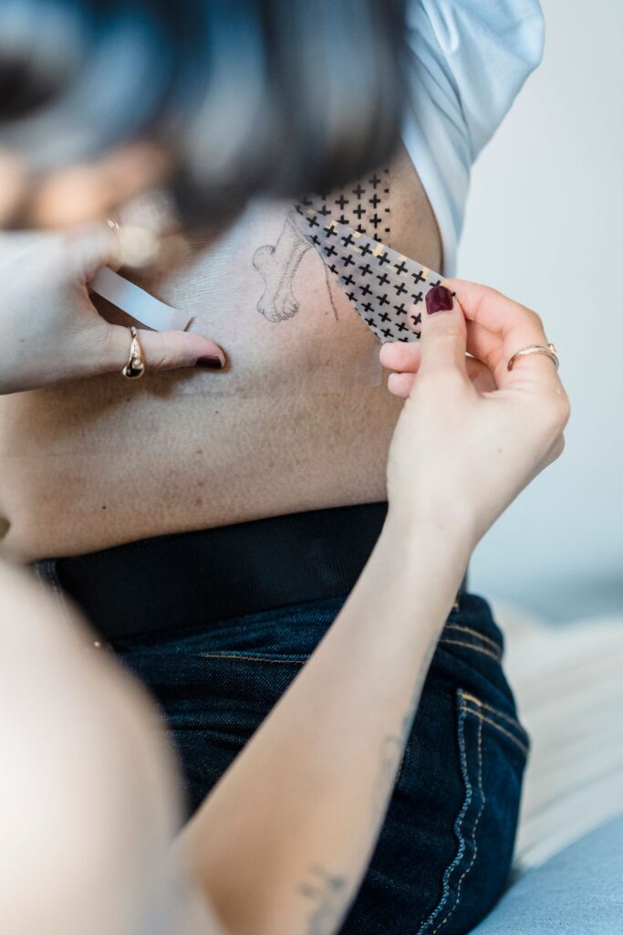 Peeling an adhesive film off the skin over a tattoo