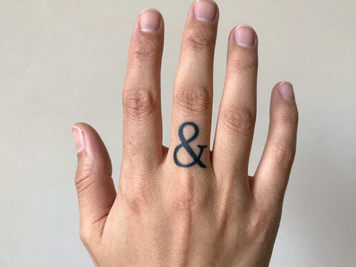 Small ampersand symbol tattoo on the finger