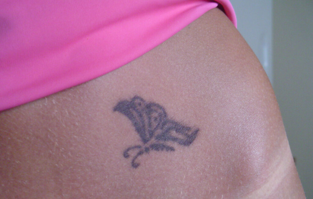 Small tribal butterfly tattoo on the lower stomach