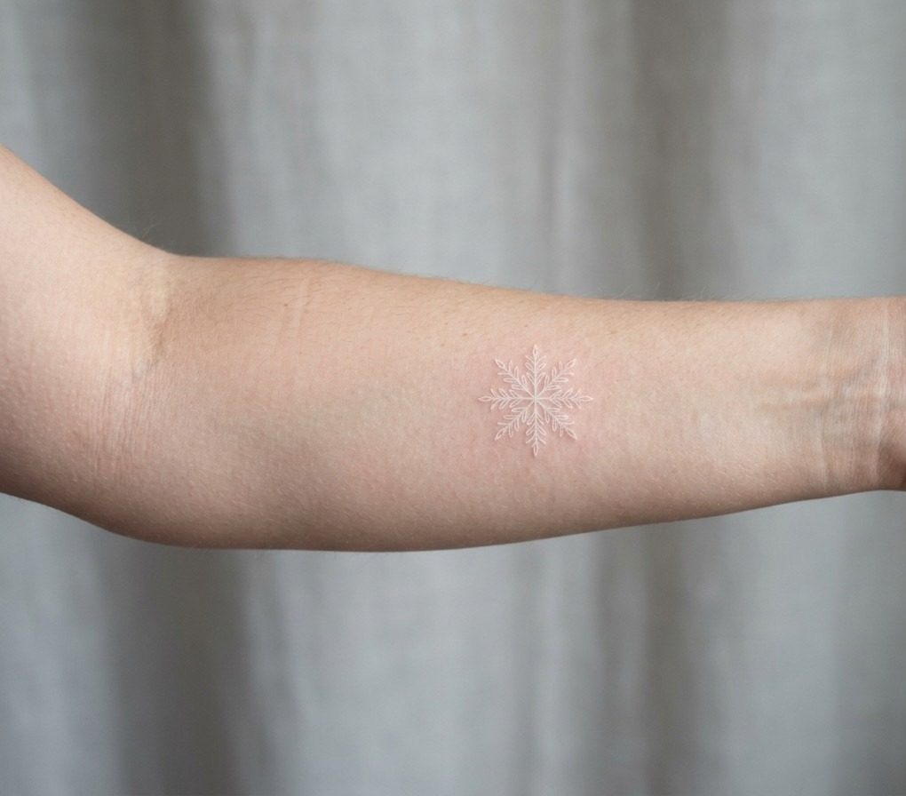 Snowflake tattoo: white ink snowflake on the inner forearm