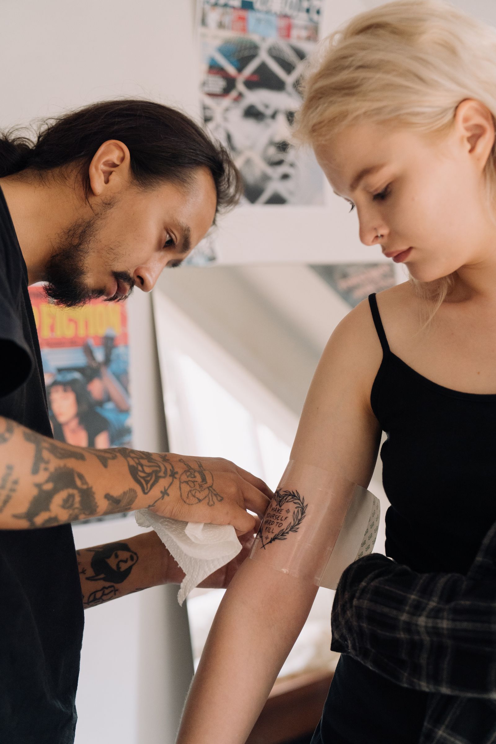 Second skin tattoo bandage being applied by a tattoo artist to a fresh arm tattoo