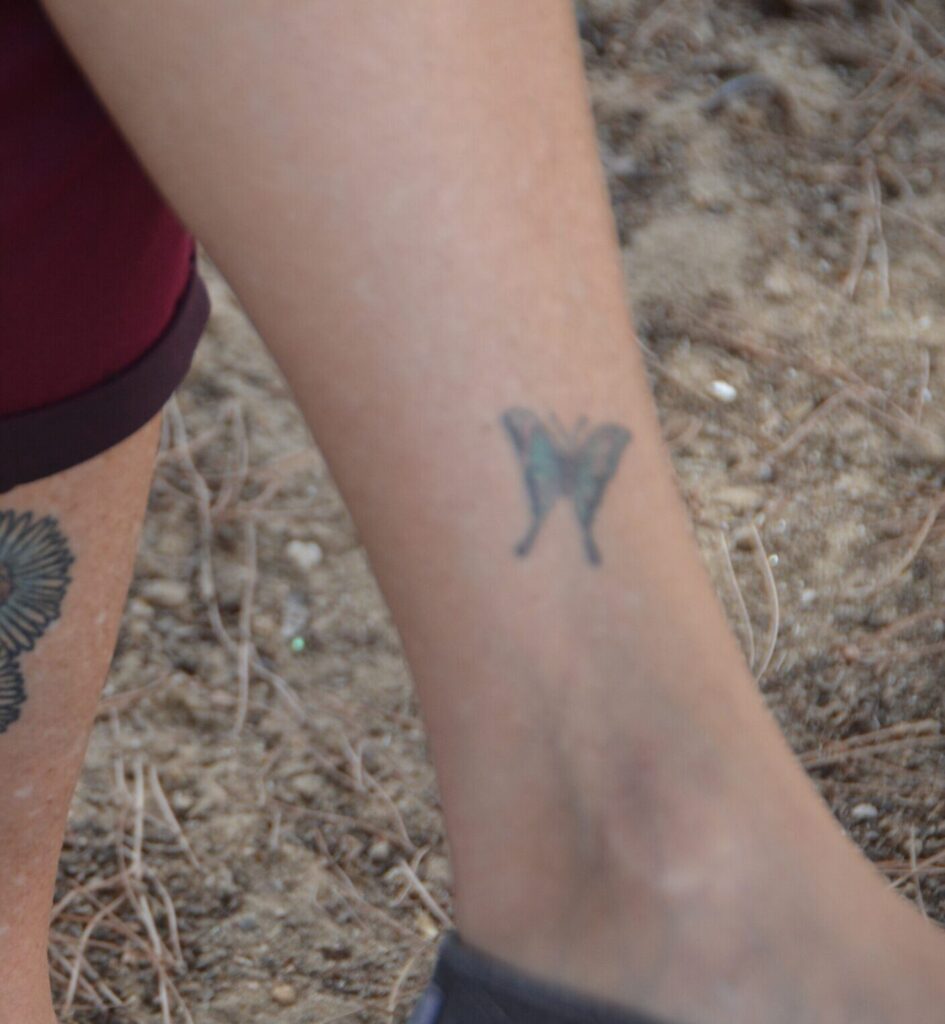 Tiny blue butterfly tattoo above the ankle