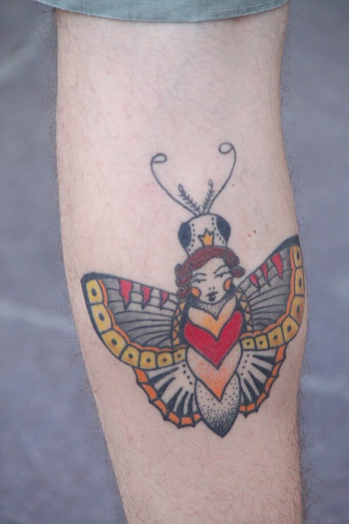 Traditional style butterfly with a woman's face tattooed on the shin